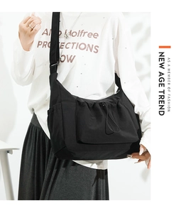 Close-up of black canvas tote bag featuring drawstring pockets and adjustable wide strap