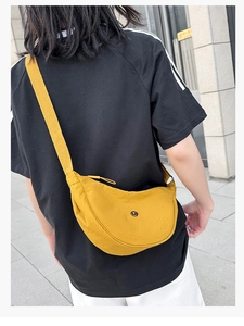 Borsa a tracolla a mezzaluna in nylon giallo indossata da una modella all'aperto