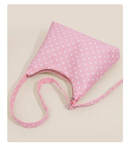Close-up of pink polka dot underarm bag featuring a metallic zipper and soft texture