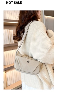 Gros plan d'un sac demi-lune en nylon beige avec bandoulière réglable sur un mannequin