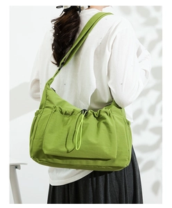 Close-up of green large-capacity canvas crossbody bag with drawstring and side pocket