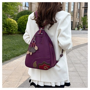 Detailed back view of purple waterproof nylon backpack with embroidery and leaf charm