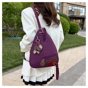 Close-up of waterproof purple oxford backpack with leaf embroidery and metal brand logo
