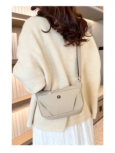 Détail du sac bandoulière beige en nylon avec design plissé et logo métallique rond
