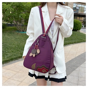Detail of waterproof purple nylon backpack featuring decorative collage and metal logo
