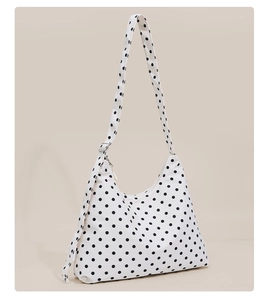 Detail shot of canvas shoulder bag featuring black polka dots and silver metal buckle
