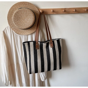Detailed texture of black and white striped straw tote with brown faux leather handles