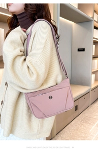 Détail du sac bandoulière en nylon rose avec sangle réglable et logo sur un tricot