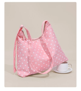 Detailed view of pink polka dot shoulder bag with wide strap and metal zipper closure
