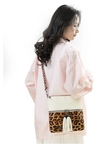 Détail de sac à bandoulière avec imprimé léopard, cuir blanc cassé et glands blancs