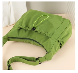 Detail of green nylon tote bag featuring adjustable drawstring pocket and wide strap