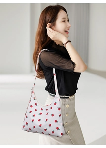 Detail shot of white shoulder bag with vibrant red strawberry print and zipper closure