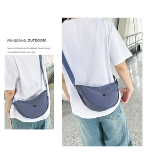 Dettaglio della borsa a mezzaluna in nylon grigio-blu con tracolla regolabile sul modello