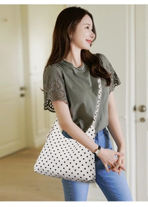 Detailed view of polka dot pattern shoulder bag on a model with natural lighting