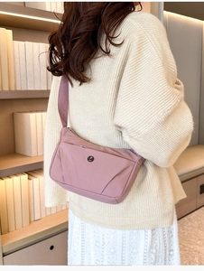 Gros plan sur un sac bandoulière en nylon rose avec logo métallique et sangle large