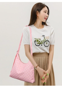 Close-up of pink polka dot underarm bag with zipper closure and wide shoulder strap