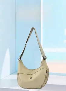 Close-up of lightweight beige oxford fabric crescent bag with zipper detail and strap