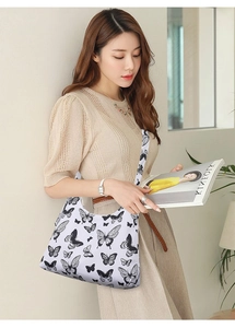 Close-up of artistic black butterfly prints on a white shoulder bag with a wide strap