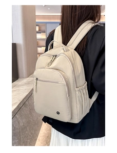 Rückansicht eines cremefarbenen Nylon-Rucksacks mit großer Fronttasche und Seitentaschen