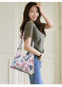 Detail of white crescent underarm bag featuring colorful butterfly patterns and canvas strap