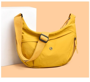 Detail of yellow nylon crescent bag featuring adjustable strap and metallic logo