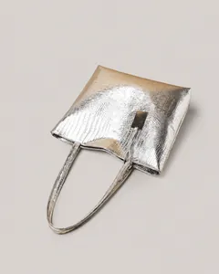 Detailed view of silver tote bag featuring elegant crocodile embossed texture and metal tag