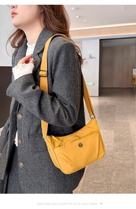 Détail du sac bandoulière en nylon jaune avec poche zippée sur un blazer gris