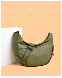 Macro shot of army green nylon crescent bag showing logo and metal zipper detail