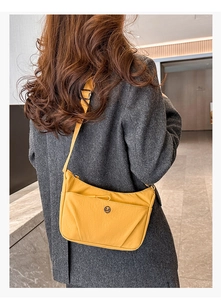 Vue détaillée d'un sac demi-lune jaune en nylon avec bandoulière et logo métal