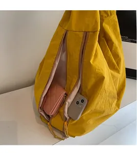 Detail of yellow nylon tote bag side zipper pocket with phone and wallet inside