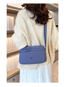 Detailansicht einer blau-violetten Umhängetasche aus Nylon mit Doppelreißverschluss und Logo