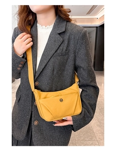 Vue détaillée du sac bandoulière en nylon jaune avec sangle portée sur un blazer gris