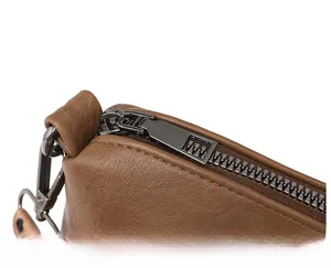 Détail d'un sac à bandoulière marron avec zip métallique et sangle à motif léopard