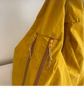 Close-up of dual smooth zippers with woven lanyards on ginger nylon tote bag