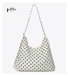 Detailed view of a white polka dot underarm bag with smooth nylon texture and zipper