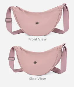 Dettaglio della borsa a mezzaluna in nylon rosa con tracolla e logo circolare