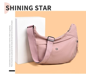 Detail of pink half-moon nylon bag showing adjustable wide strap and metallic logo
