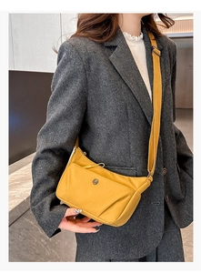 Détail d'un sac bandoulière en nylon jaune vif avec logo métallique et sangle réglable