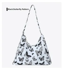 Detail of white underarm bag featuring all-over black butterfly print and canvas strap