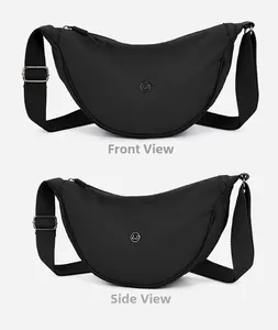 Dettaglio borsa a mezzaluna in nylon nero con logo in metallo e tracolla larga