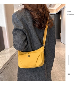 Détail du sac bandoulière en nylon jaune porté sur un manteau de laine gris