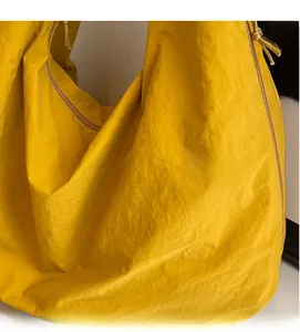 Detail of yellow nylon tote bag featuring crinkled fabric texture and side zipper detail