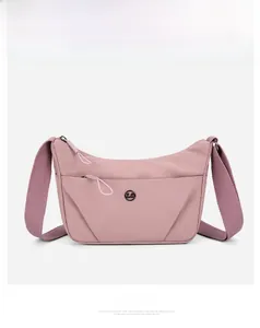 Détail du sac bandoulière en nylon rose avec logo circulaire et poche zippée