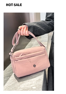 Details einer rosa Nylon-Umhängetasche mit mehreren Reißverschlussfächern und Logo