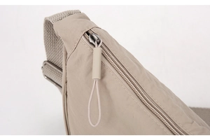 Dettaglio della borsa a tracolla in nylon beige con cerniera in metallo e tracolla rinforzata