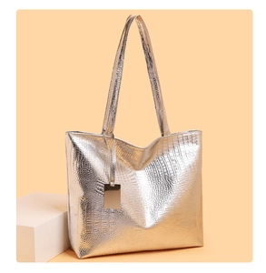 Detail van zilveren shopper met krokodillenmotief, metallic glans en gouden hanger