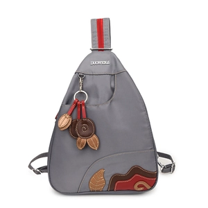 Waterproof grey nylon teardrop sling bag with decorative embroidery and red zippers