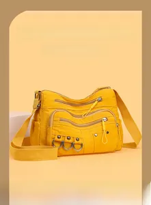 Detail of yellow nylon crossbody bag with multiple zippers and wide fabric strap
