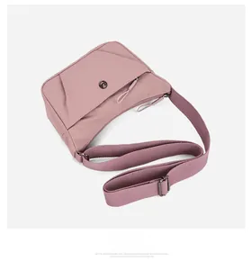 Détail d'un sac bandoulière en nylon rose avec sangle réglable et boucle en métal argenté