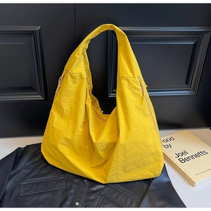 Detail of ginger yellow nylon tote bag showing its wrinkled texture on a leather jacket